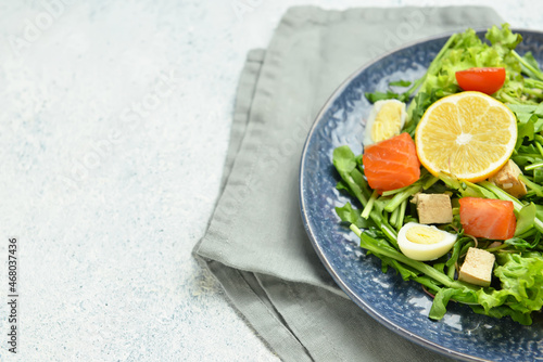 Fresh salad with salmon and vegetables in plate on light background, closeup