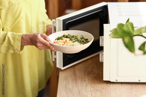 Mature woman heating food i...