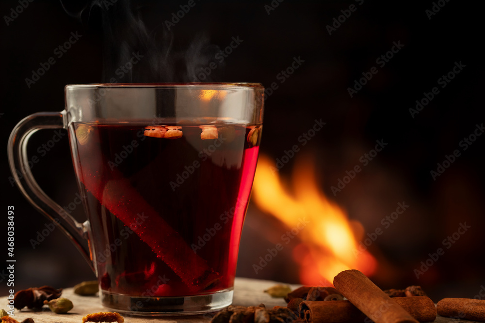 Glass mug with hot mulled wine by the burning fireplace