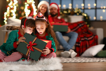 Surprised little brother and sister opening present at home on Christmas eve