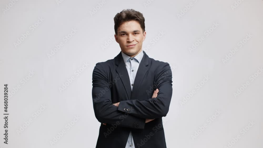 Studio portrait of young confident top manager wearing formal suit posing to camera with folded arms, white background Studio portrait of young confident top manager wearing formal suit posing to camera with folded arms, white background