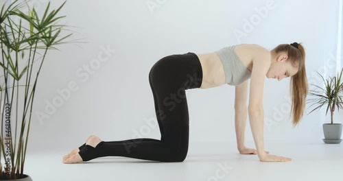 Side view young woman in cat-cow pose. Girl practices yoga, Marjariasana. Exercise for healthy back. photo
