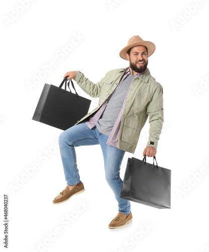 Handsome man with Black Friday shopping bags jumping on white background photo