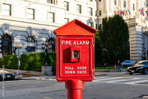 Vintage fire alarm red pull box on a city street. Blurred urban background. Close up. photo