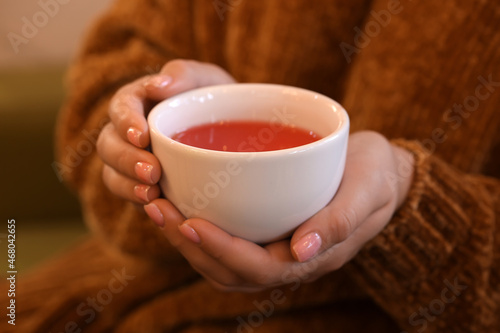 Woman with cup of hot tea in cafe, closeup