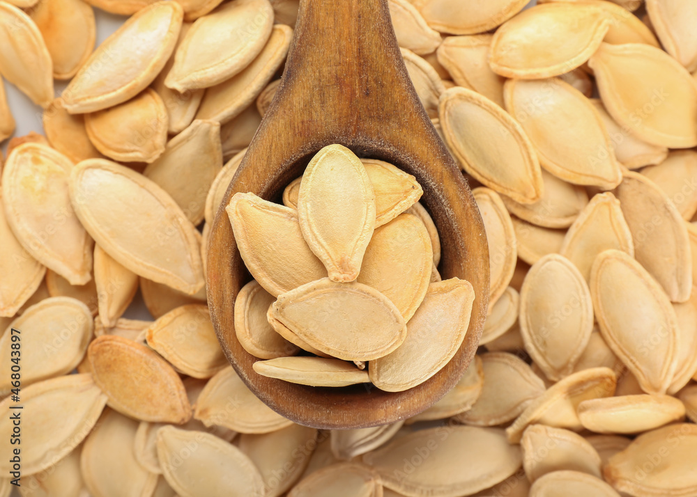 Spoon and natural pumpkin seeds as background, closeup Spoon and natural pumpkin seeds as background, closeup