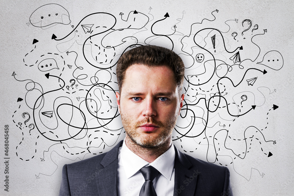 Portrait of attractive young european businessman on concrete wall background with arrows and thought icons sketch. Solution, direction, success and brainstorm concept. Portrait of attractive young european businessman on concrete wall background with arrows and thought icons sketch. Solution, direction, success and brainstorm concept.