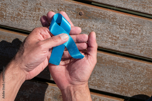Prostate cancer awareness, man's hand holding a light blue ribbon to support people living and disease. World Cancer Day and Men's Health Concept