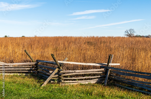 A wooden fence with a wheat field behind it at the Gettysburg National Military Park on a sunny fall day