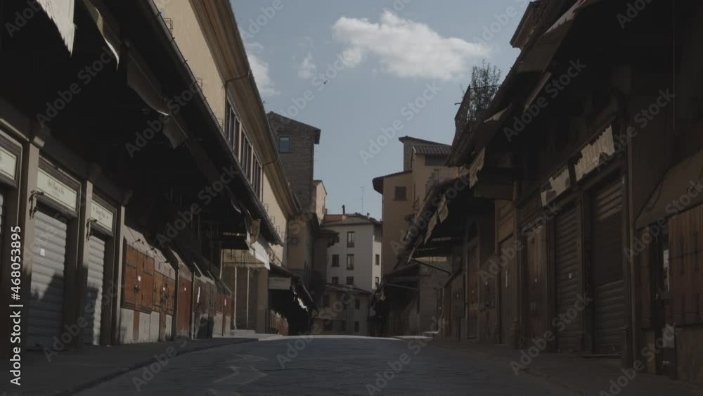 Ponte Vecchio in Florence with closed jewelry without people walking and some birds flying medium shot during lockdown in Italy Ponte Vecchio in Florence with closed jewelry without people walking and some birds flying medium shot during lockdown in Italy