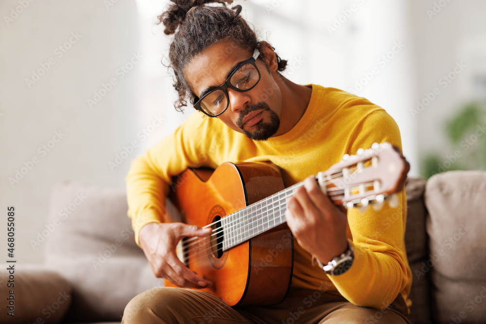 Young joyful african american man playing acoustic guitar at home, sitting  on sofa in living room Stock-Foto | Adobe Stock