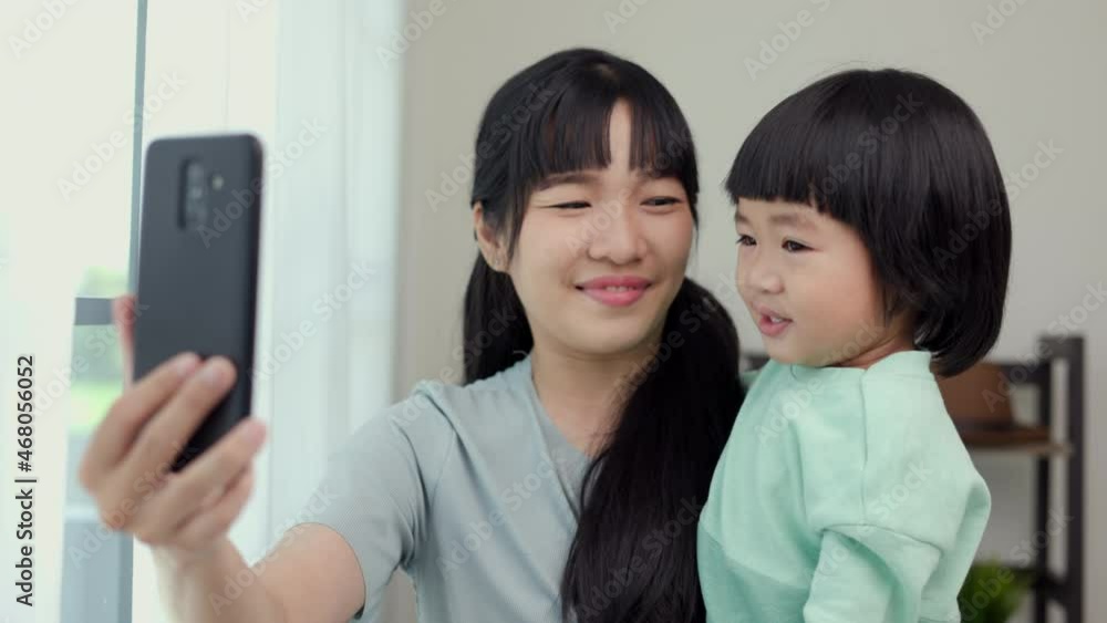 Mom carry son using smartphone video call to say hi with family stay at home. Mother holding little boy hugging shared happy moment on social media walking in living room. Mom carry son using smartphone video call to say hi with family stay at home. Mother holding little boy hugging shared happy moment on social media walking in living room.