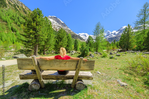 Backpacker girl with red t-shirt on the trekking bench to Morteratsch glacier of Switzerland. Biggest glacier in Bernina Range of the Bundner Alps in Grisons Graubunden Canton of Switzerland. photo