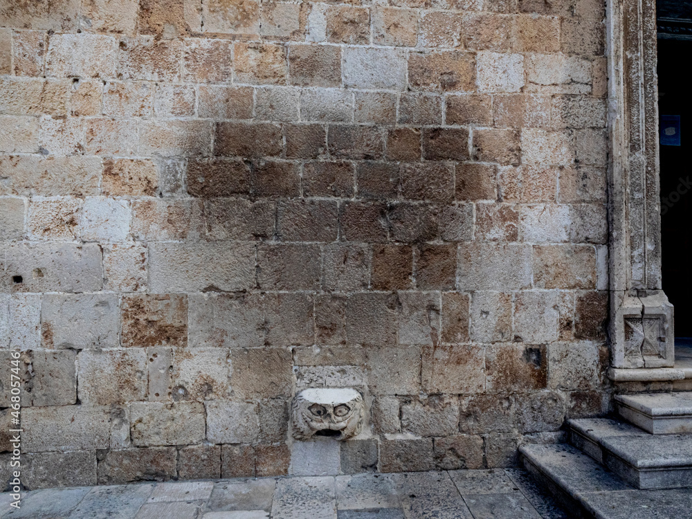 Impression left by people trying to get good luck by balancing on the stone Maskeron legend gargoyle set in a wall of Dubrovnik, Croatia. Impression left by people trying to get good luck by balancing on the stone Maskeron legend gargoyle set in a wall of Dubrovnik, Croatia.