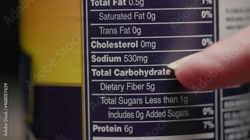 A woman checks the ingredient list on the product label of a canned product and focuses on the high sodium content.