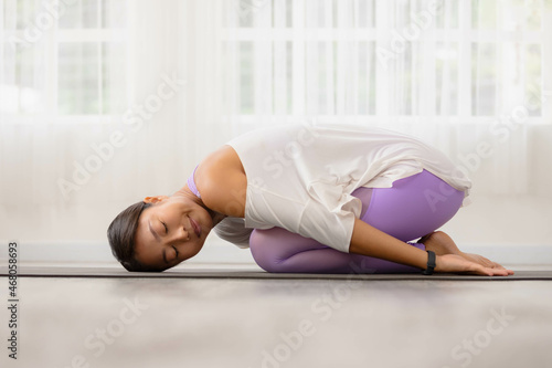 Asian woman working out in sportswear while doing yoga, seated in Child exercise, Balasana stance.