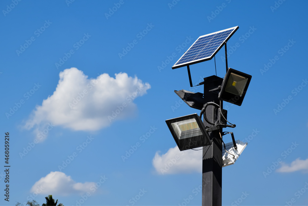 Photovoltaic panel systems and hd floodlights on black metal pole in public park, soft and selective focus. Photovoltaic panel systems and hd floodlights on black metal pole in public park, soft and selective focus.
