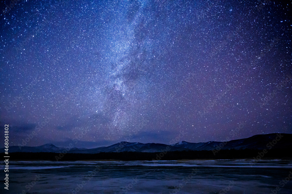 Starry sky over a frozen winter lake. Milky Way. Sikhote-Alin Biosphere Reserve in the Primorsky Territory.
