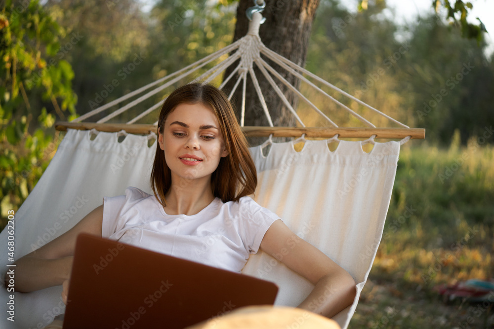 Naklejka premium woman with laptop and lies in a hammock vacation nature freelance