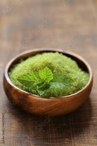 cosmetics salt with Peppermint extract.green sea salt in a round bowl and sprigs of peppermint on a wooden table. Natural cosmetics and aromatherapy.Organic natural cosmetics for body 