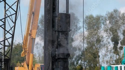 Pile-driving (copra) part of the excavator in close-up. Pile driving works at the construction site. Modern hydraulic lifting mechanisms. photo