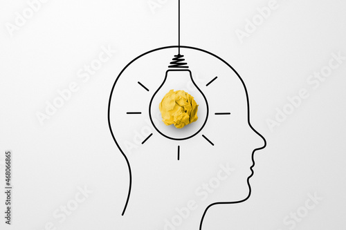 Concept creative idea and innovation. Paper scrap ball yellow colour and light bulb in head human symbol photo