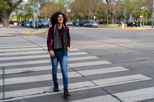 portrait of a young Latin man with curly hair crossing the street on the pedestrian path. © HC FOTOSTUDIO