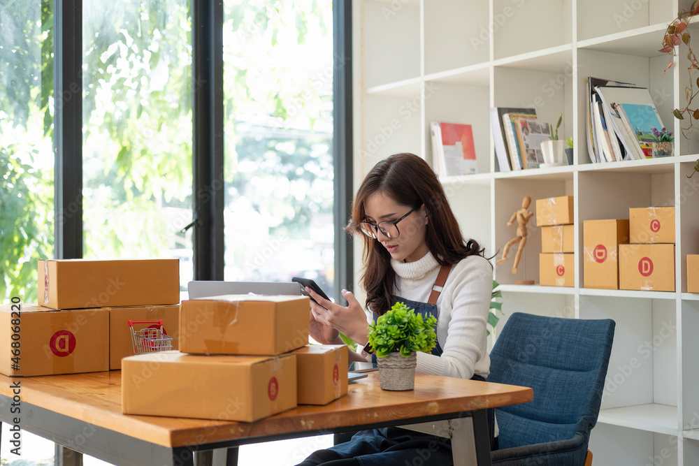 Starting Small business entrepreneur SME freelance,Portrait young woman working at home office, BOX,smartphone,laptop, online, marketing, packaging, delivery, SME, e-commerce concept. Starting Small business entrepreneur SME freelance,Portrait young woman working at home office, BOX,smartphone,laptop, online, marketing, packaging, delivery, SME, e-commerce concept.