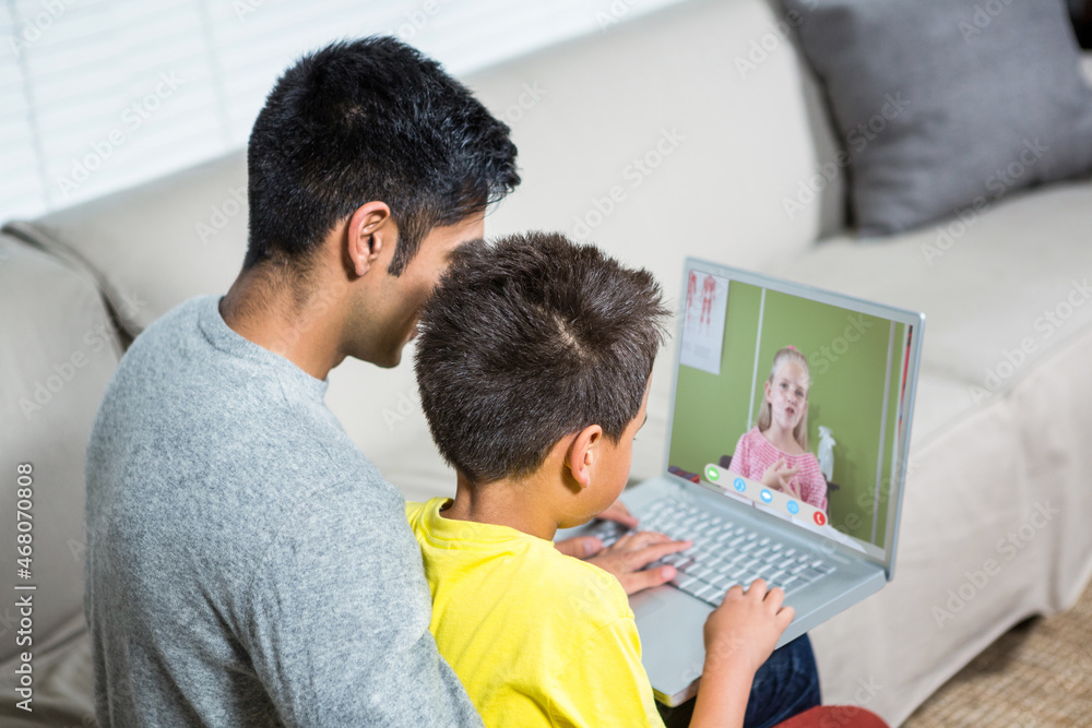 Biracial boy with father using laptop for video call, with elementary school pupil on screen Biracial boy with father using laptop for video call, with elementary school pupil on screen