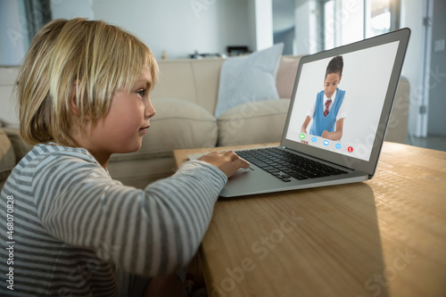 Caucasian boy using laptop for video call, with elementary school pupil on screen