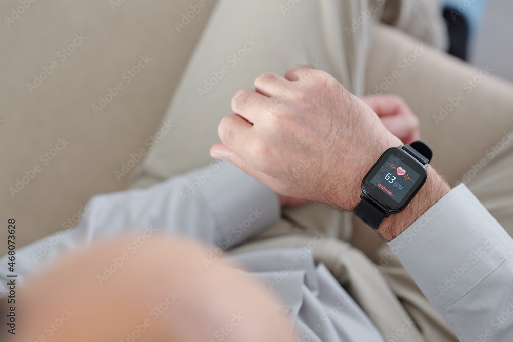 Man using application on smartwatch to control his heart rate, view from above