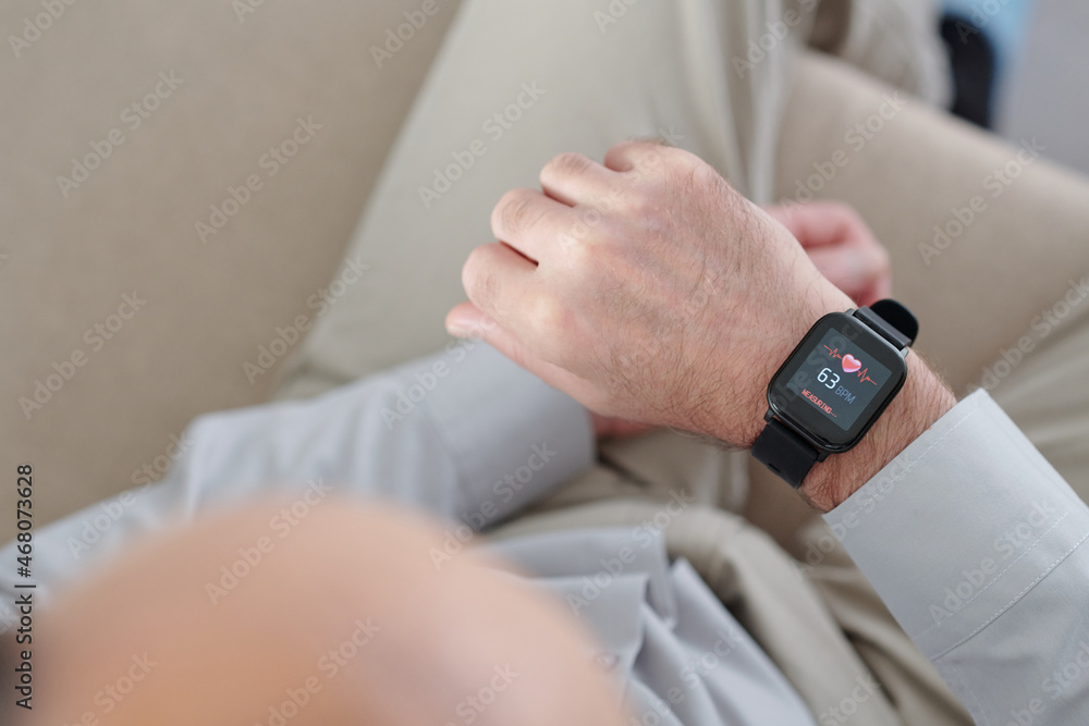 Man using application on smartwatch to control his heart rate, view from above Man using application on smartwatch to control his heart rate, view from above