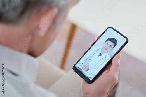 Senior man video calling his cardiologist whe suffering from heartache photo