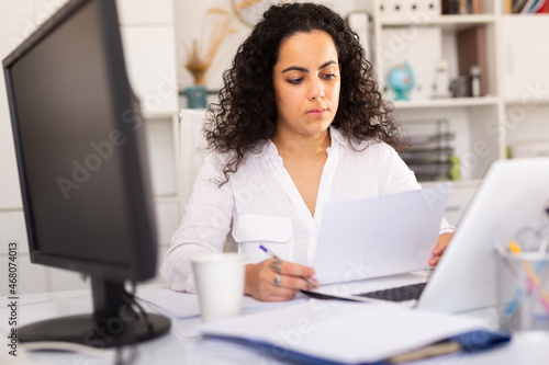 Office woman worker is working with documents and laptop in the office