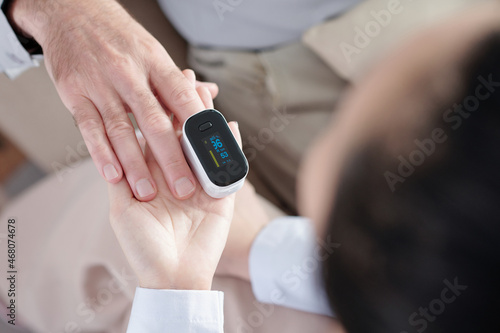 Close-up image of senior man letting his doctor to check his saturation with help of pulse oximeter device