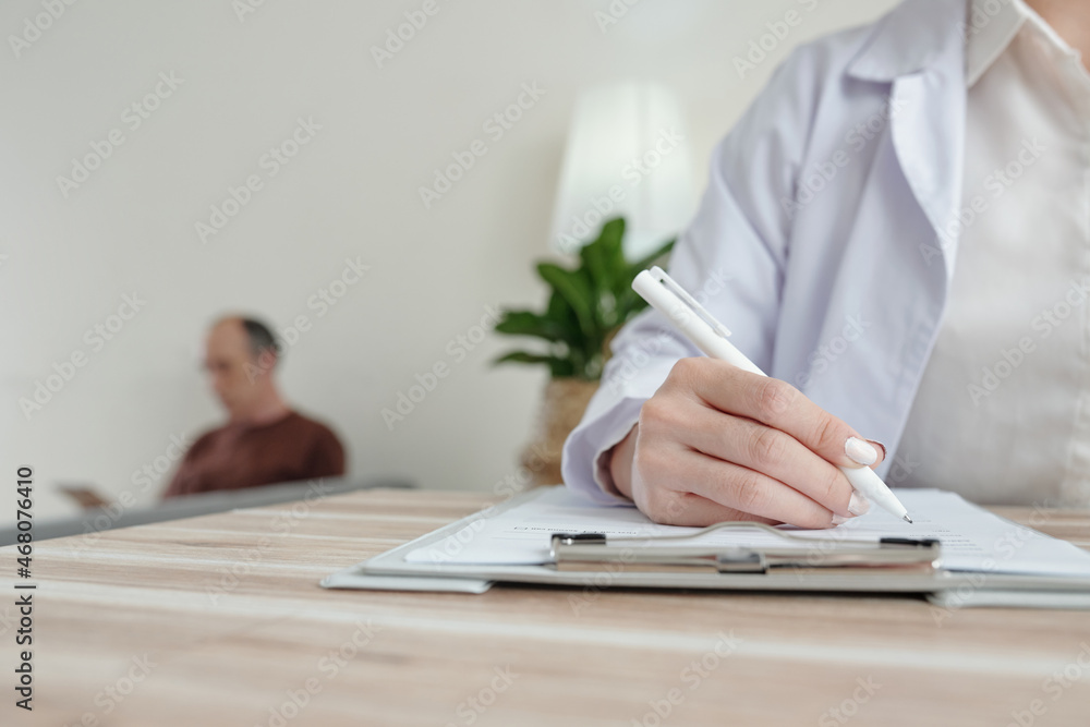 Close-up image of doctor filling medical documents at her office table and writing out prescription for senior patient Close-up image of doctor filling medical documents at her office table and writing out prescription for senior patient