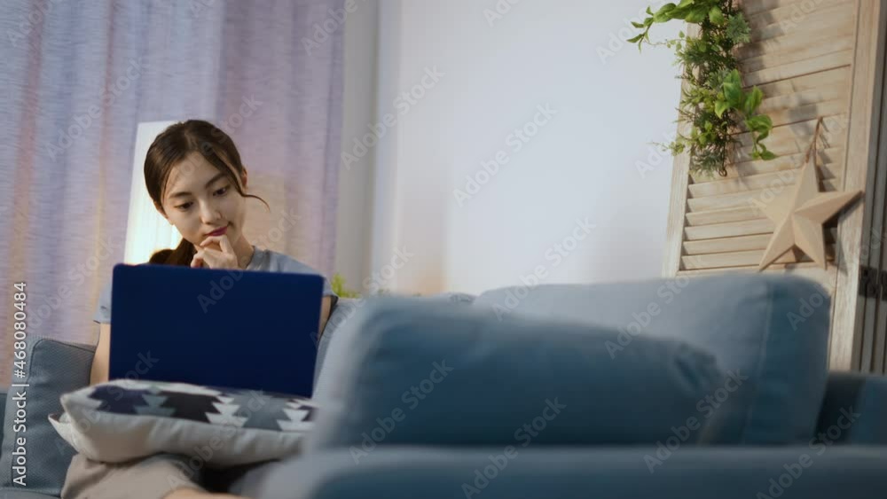 ソファーでノートパソコンを使う若い女性 ソファーでノートパソコンを使う若い女性