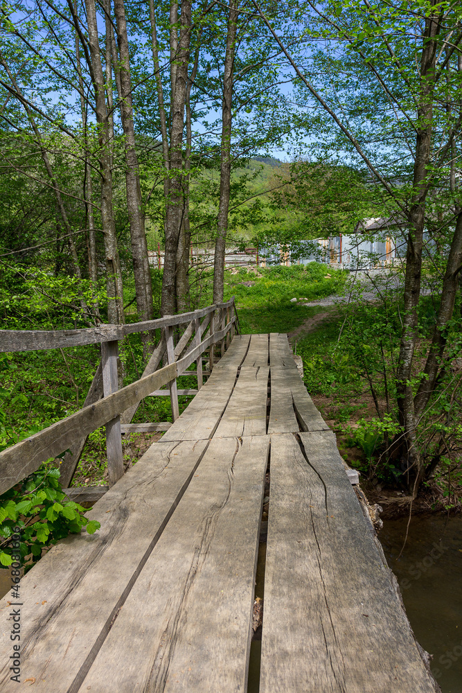 Wooden bridge, in summer in a mountain chalet, crossing a small river in retro style. Wooden bridge, in summer in a mountain chalet, crossing a small river in retro style.