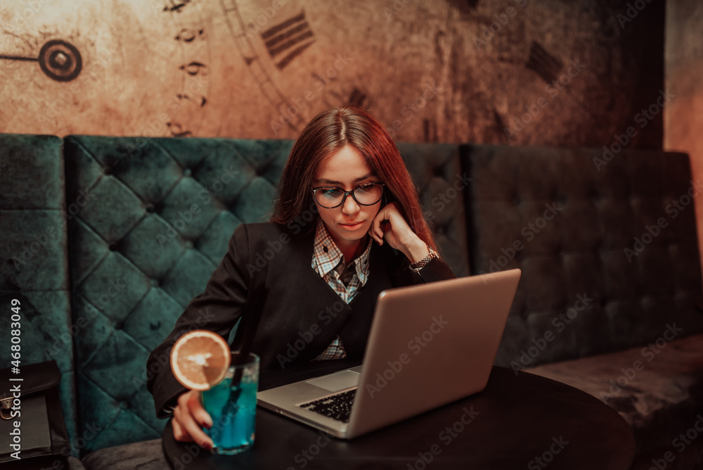 Tired young student girl studying online while sitting with laptop and notebook in cafeteria female freelancer resting her face on hand with lack of facial expression looks to side. Selective focus Tired young student girl studying online while sitting with laptop and notebook in cafeteria female freelancer resting her face on hand with lack of facial expression looks to side. Selective focus