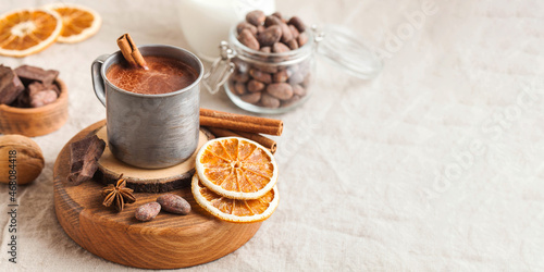 Banner hot chocolate in a metal mug with a cinnamon stick on the tablecloth. Copy space