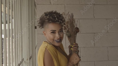 Enclosed African American Woman Dressed In Yellow Smelling Dried Flowers. Conceptual and methaphoric estabilized footage photo