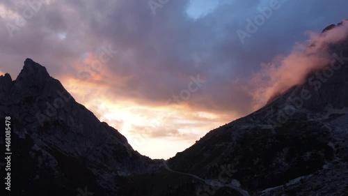 Beautiful fiery sunset beyond the mountains of Dolomites, Italy -Aerial photo