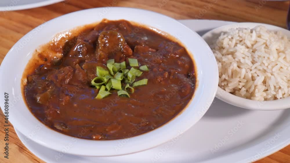 Woman takes a spoonful of gumbo, spoon scoops a biteful of dark rich cajun gumbo, slider HD Woman takes a spoonful of gumbo, spoon scoops a biteful of dark rich cajun gumbo, slider HD