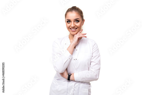 Photo of a beautiful pretty cute attractive positive smiling young blonde woman with a ponytail and makeup in a white medical coat of a nurse isolated on a white background with free and copy space © Ivan Traimak