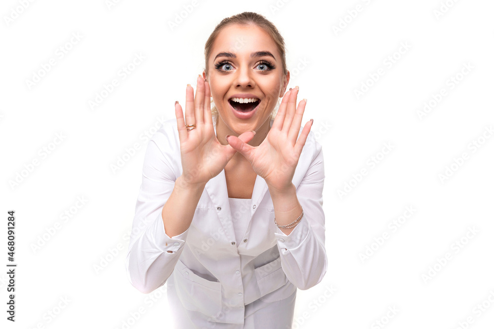Photo of a beautiful pretty attractive positive young blonde woman with a ponytail and makeup in a white medical coat of a nurse shouts with open mouth isolated on a white background with free and Photo of a beautiful pretty attractive positive young blonde woman with a ponytail and makeup in a white medical coat of a nurse shouts with open mouth isolated on a white background with free and