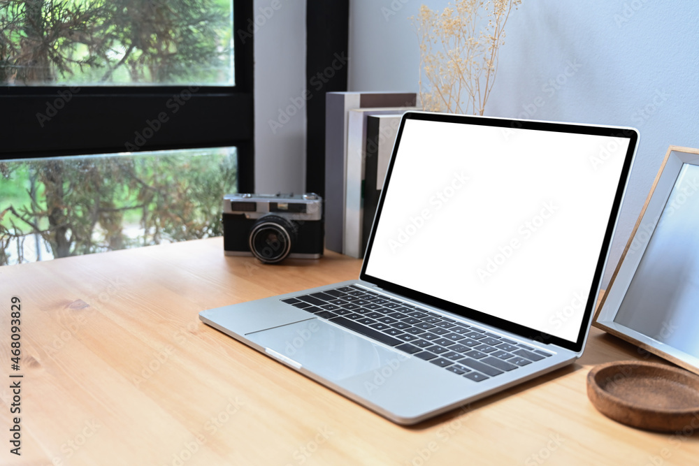 Laptop computer with blank screen, camera and books on wooden table. Laptop computer with blank screen, camera and books on wooden table.