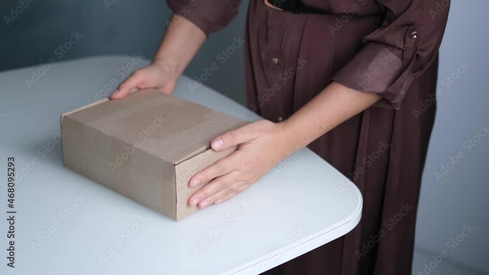 woman opening parcel indoors. woman opening and unpacking cardboard box parcel in living room at home. good delivery service. woman opening parcel indoors. woman opening and unpacking cardboard box parcel in living room at home. good delivery service.