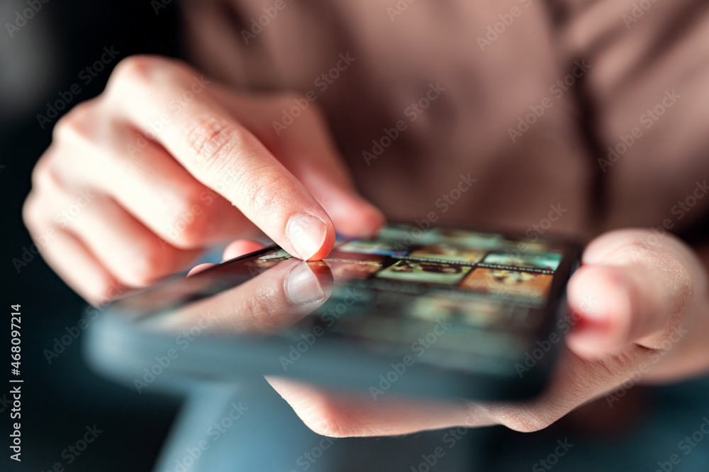 Online movie stream with mobile phone. hand of woman choosing film on smartphone with imaginary video player service. Online movie stream with mobile phone. hand of woman choosing film on smartphone with imaginary video player service.
