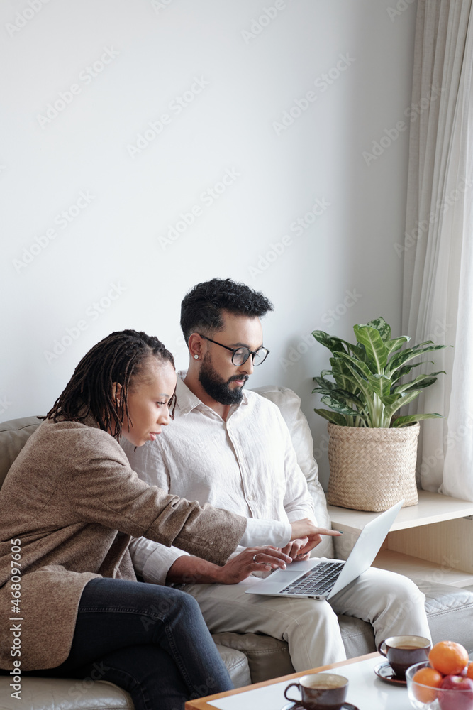 Business couple sitting on sofa at home and discussing online shop they just lauched
