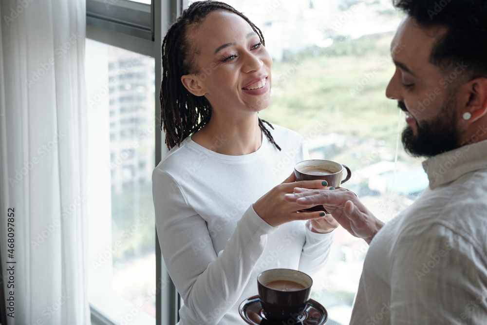 Positive devirse couple standing at apartment window and enjoying delicious morning coffee Positive devirse couple standing at apartment window and enjoying delicious morning coffee